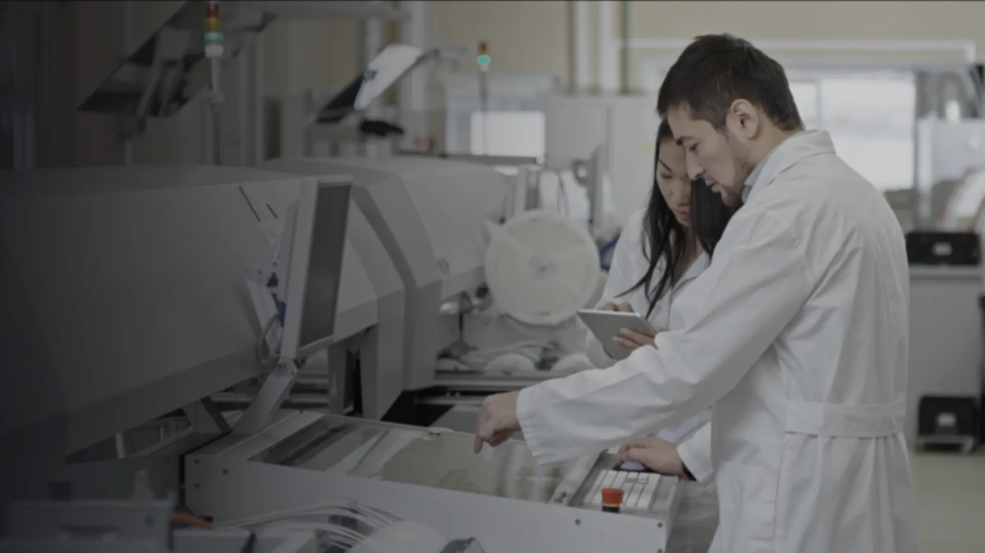 Two specialists working together at a production machine, one with a tablet