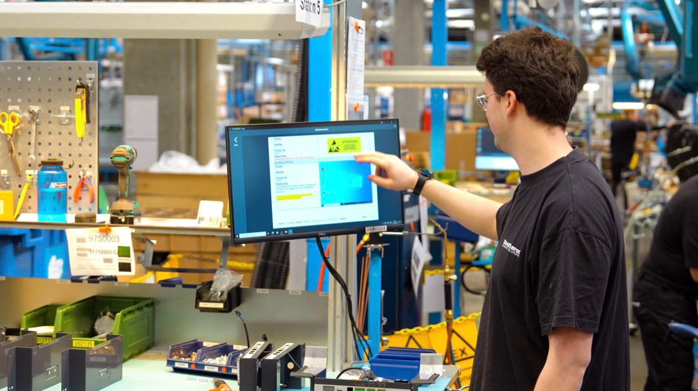 Werker betrachtet digitale Arbeitsanweisung aus bestehenden SOPs an einer Fertigungsstation