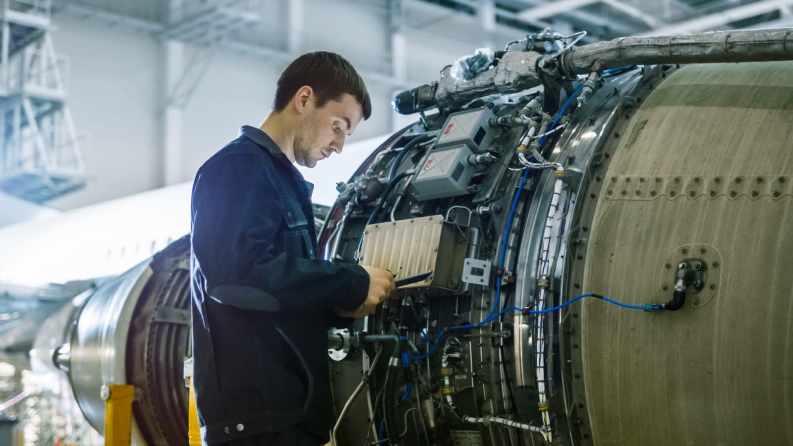 Aircraft maintenance mechanic inspecting airplane jet engine in hangar