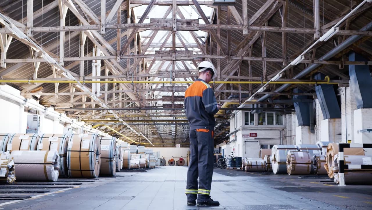 Worker in safety gear on a walk through a plant hall