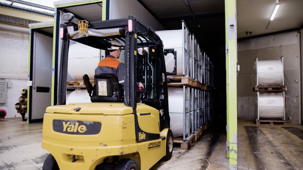 Forklift operator loading steel coils in an industrial warehouse