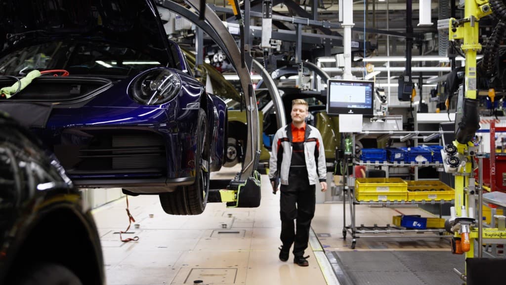 Production worker walking alongside a vehicle on an automotive assembly line